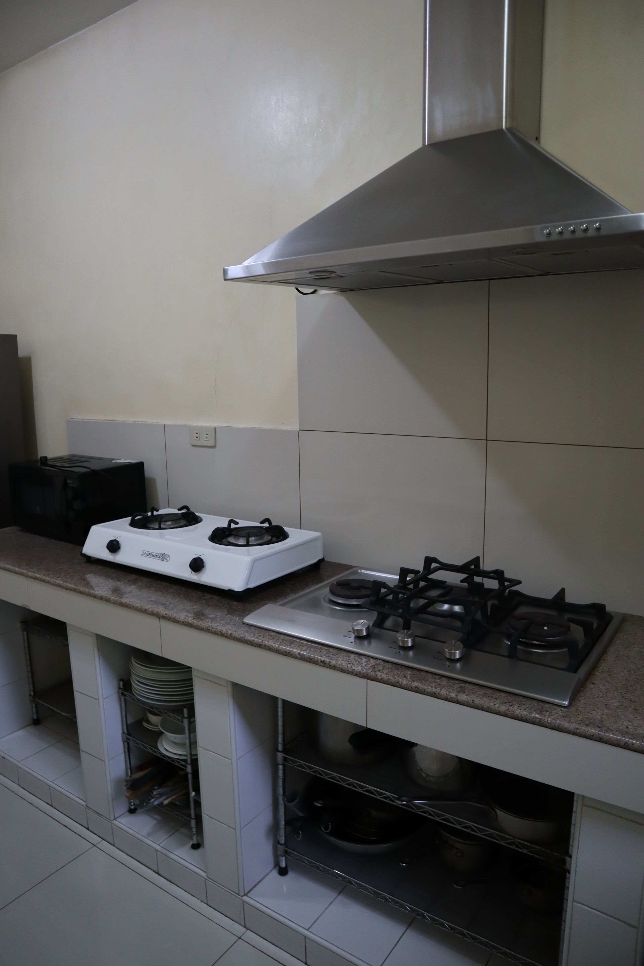 A kitchen with a white stove, black burners, and a stainless steel range hood.