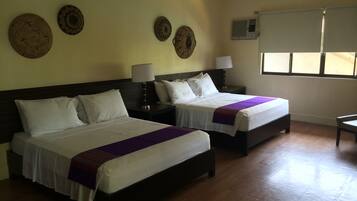 Habitación de hotel con dos camas, pisos de madera y paneles decorativos en la pared.