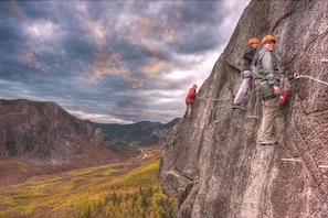 Un groupe d’alpinistes sur une paroi rocheuse escarpée, avec une vallée en contrebas.