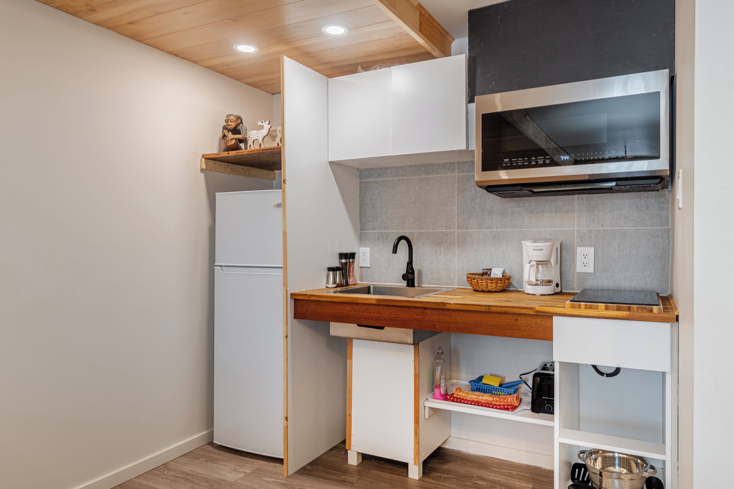 A compact kitchen with a built-in refrigerator, a microwave, and a sink.