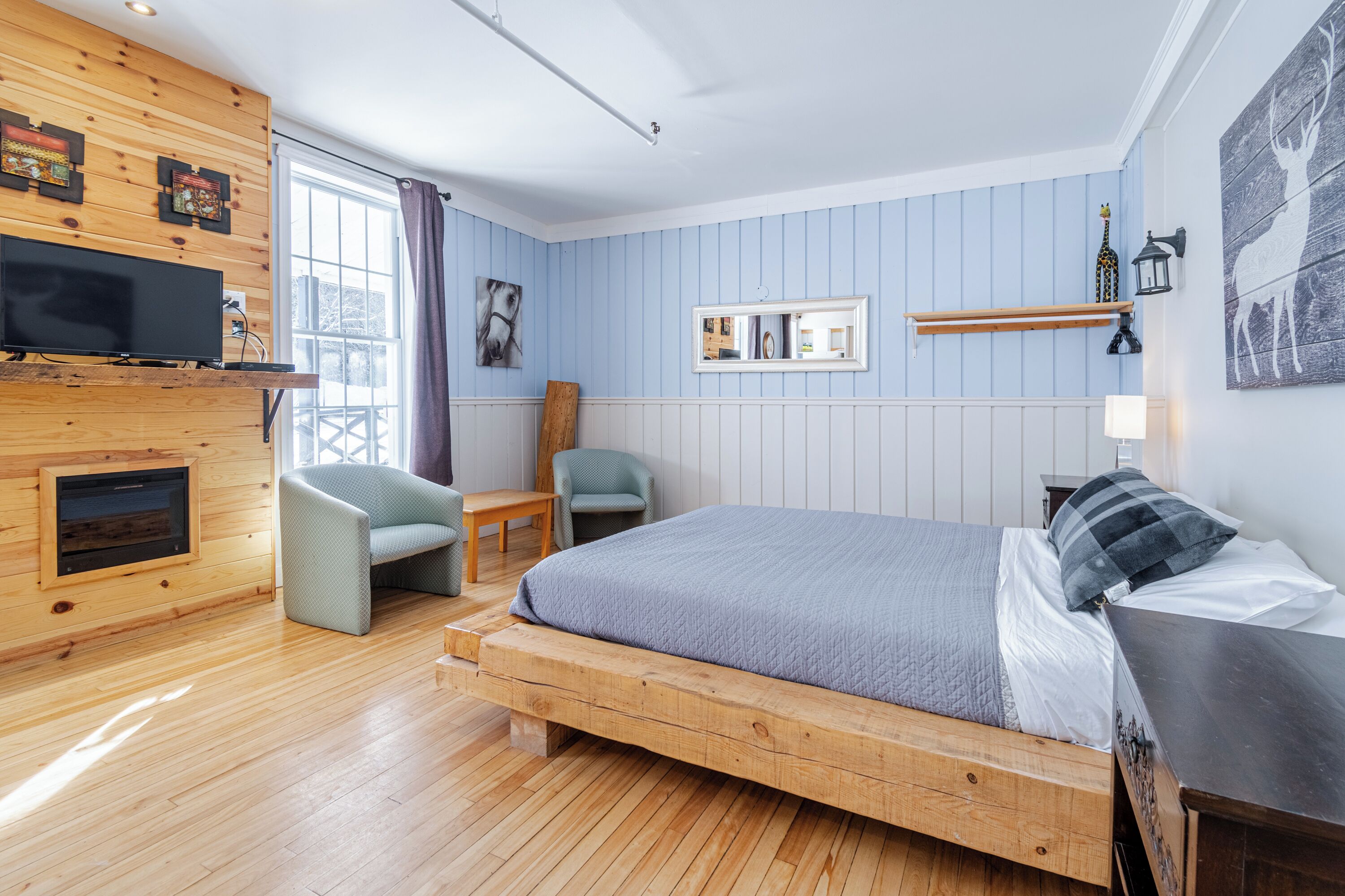 Una habitación con cama, televisión, sillón, mesa y chimenea.