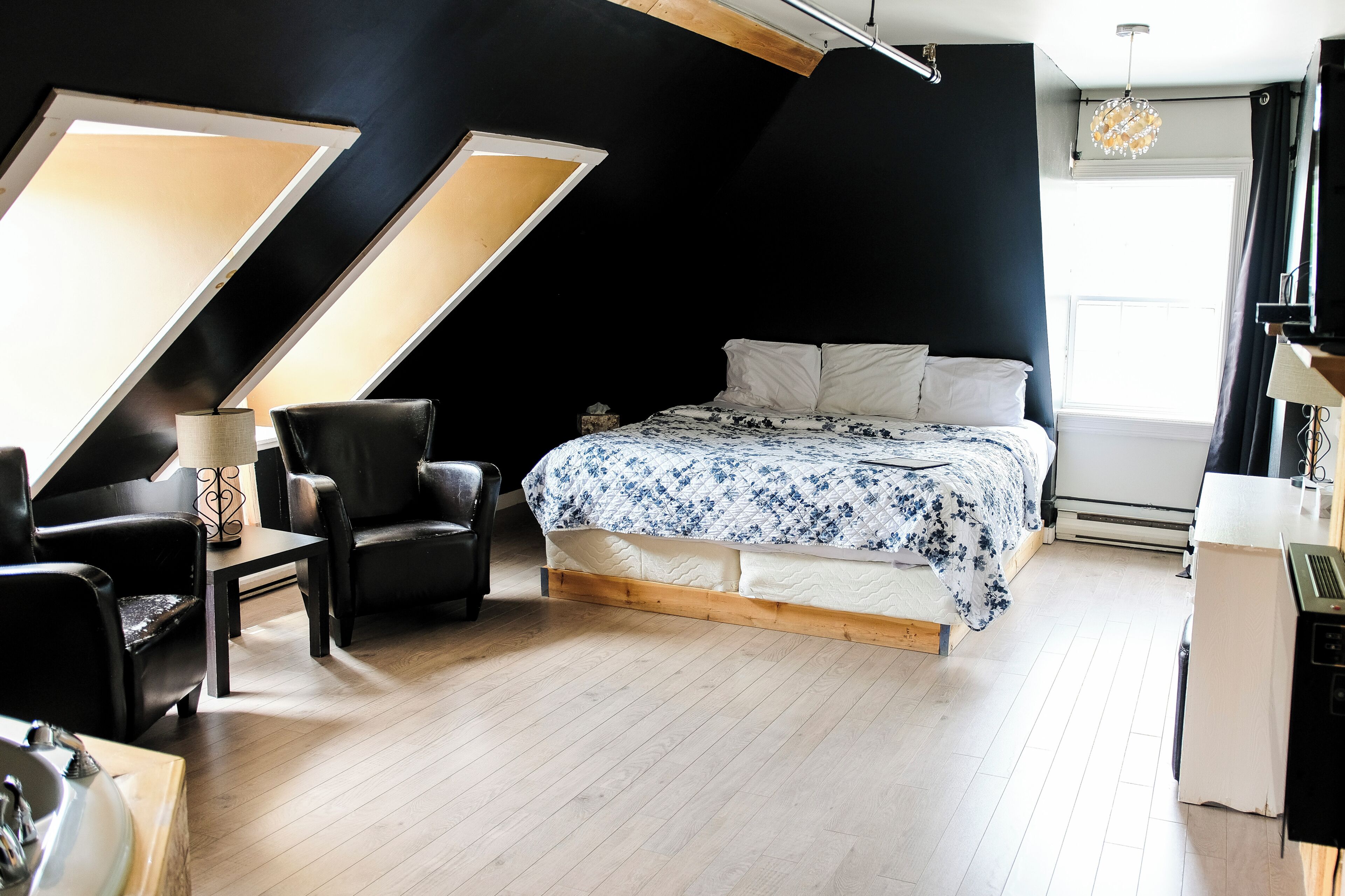 A modern bedroom with a bed, a chair, a desk, and a lamp.