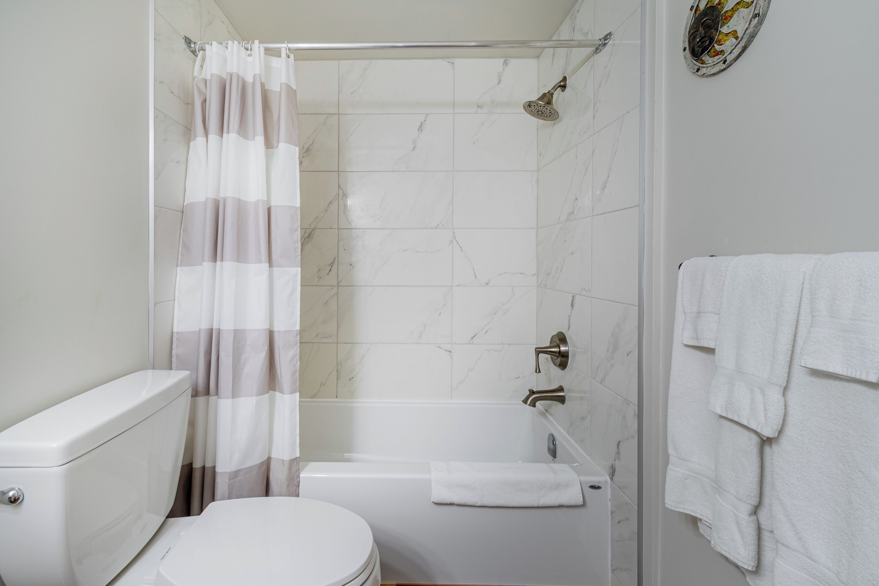 A bathroom with a toilet, a shower with a curtain, a bathtub, and a towel rack.