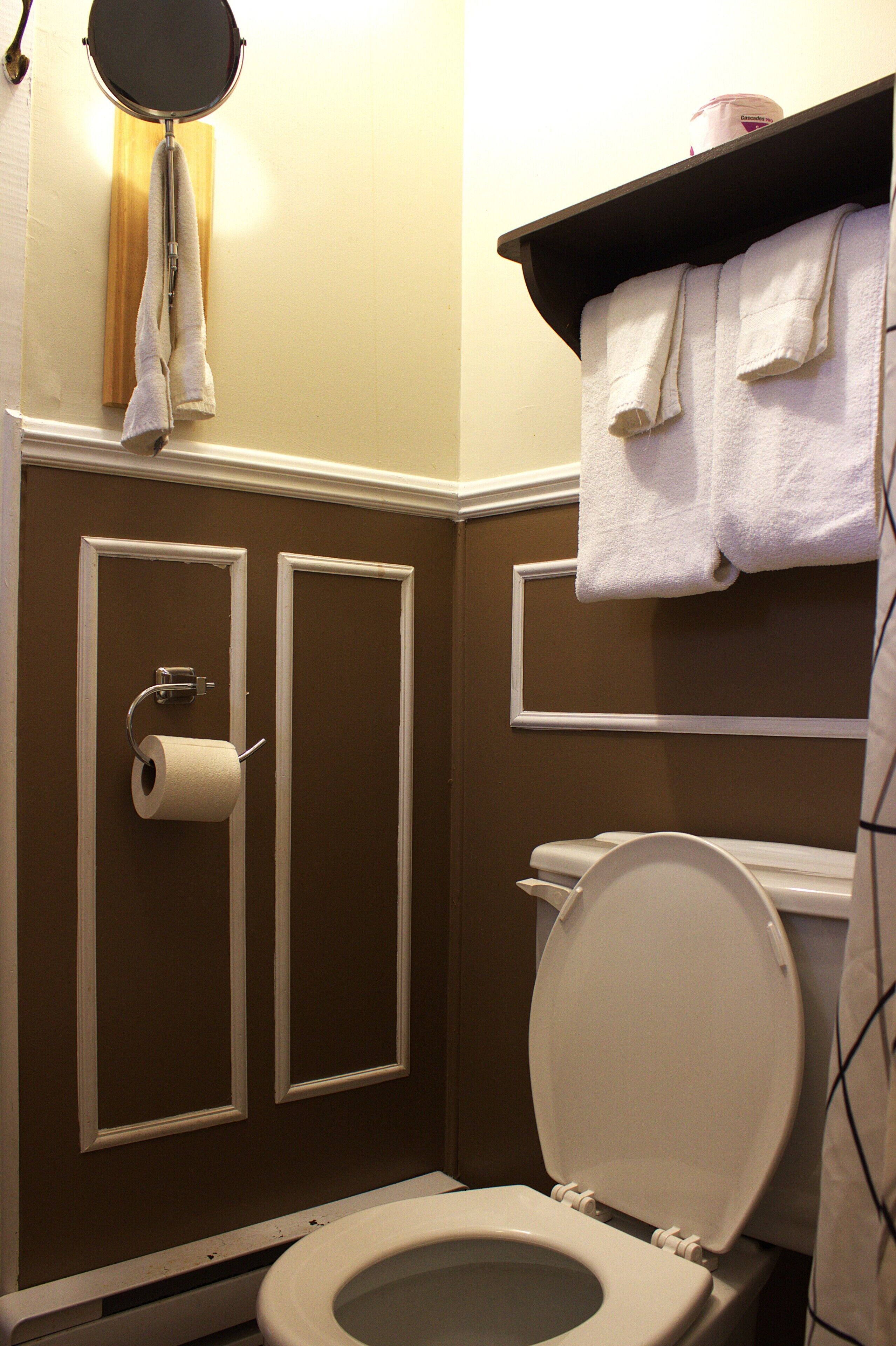A bathroom with a toilet, a towel rack, and a toilet paper holder.