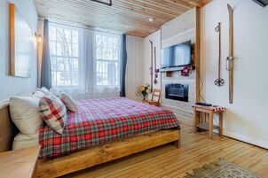 Quarto com cama de madeira, televisão, esquis e lareira.