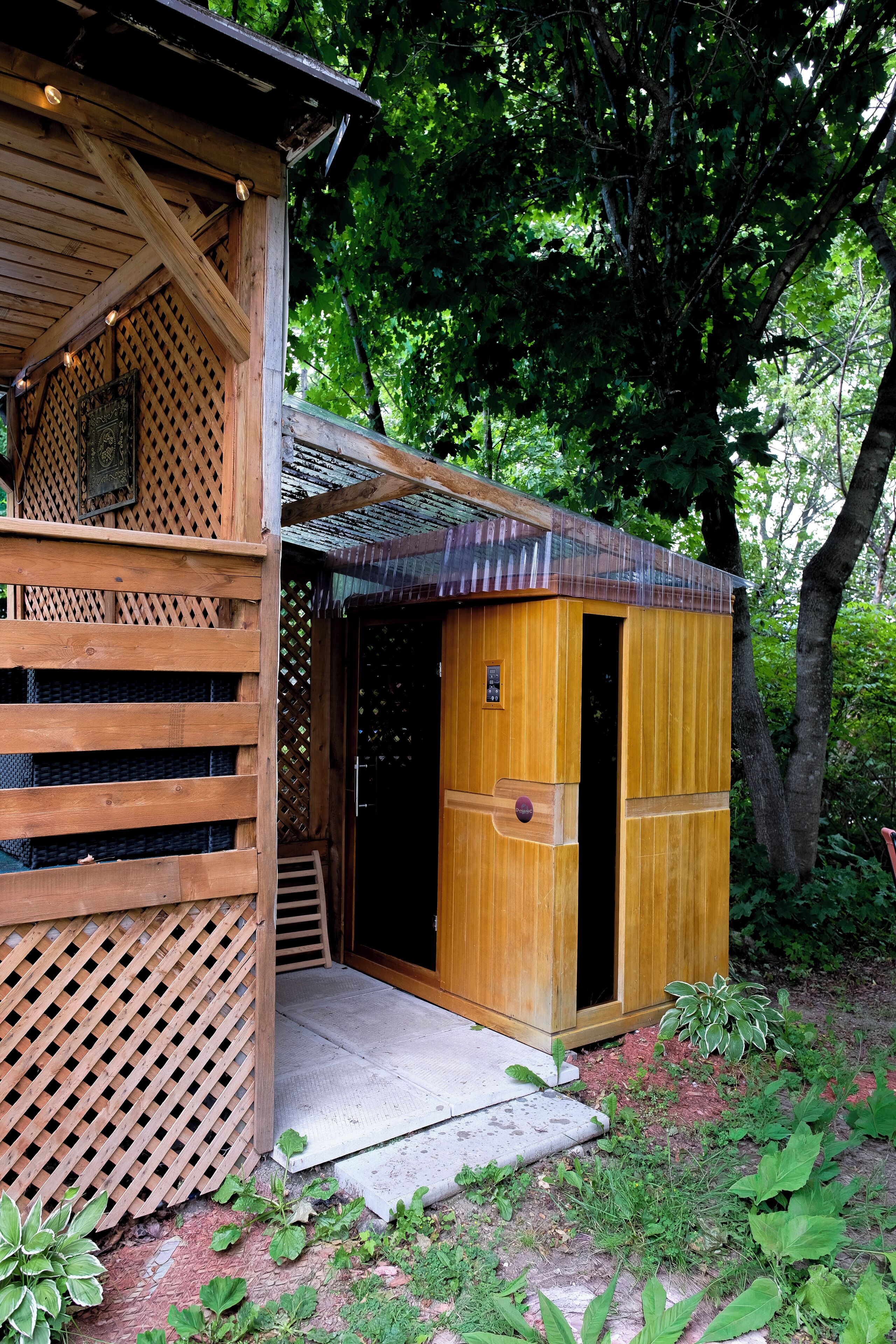 Una cabaña de madera con entrada enrejada, una puerta pequeña y un porche cubierto.