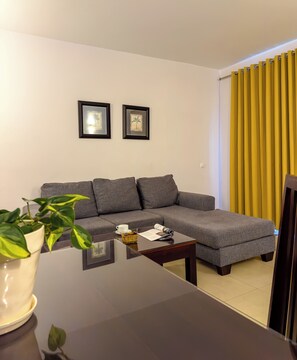 A modern living room with a grey sectional sofa, a small coffee table, and a potted plant. - VIP Executive Suites Maputo Hotel (Maputo)