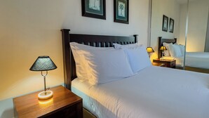 A hotel room with a bed, a bedside table with a lamp, a small rug, and two framed pictures on the wall. - VIP Executive Suites Maputo Hotel (Maputo)