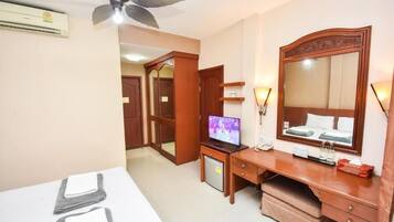 Une chambre d’hôtel équipée d’un lit, d’un bureau, d’une télévision, d’un miroir et d’un ventilateur de plafond.