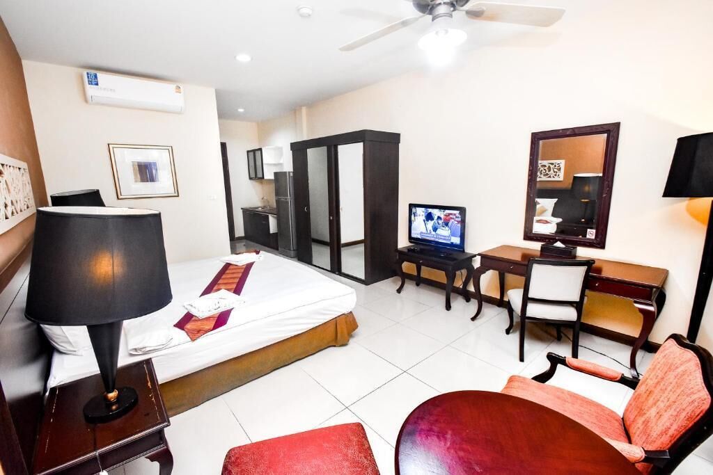 Una habitación de hotel con cama, escritorio, silla, televisor y ventilador de techo.