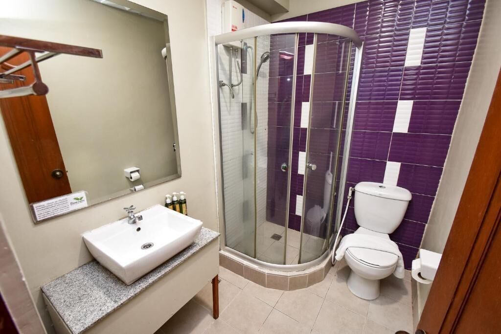 Ein Badezimmer mit weißem Waschbecken, einer Duschkabine und einer Toilette.