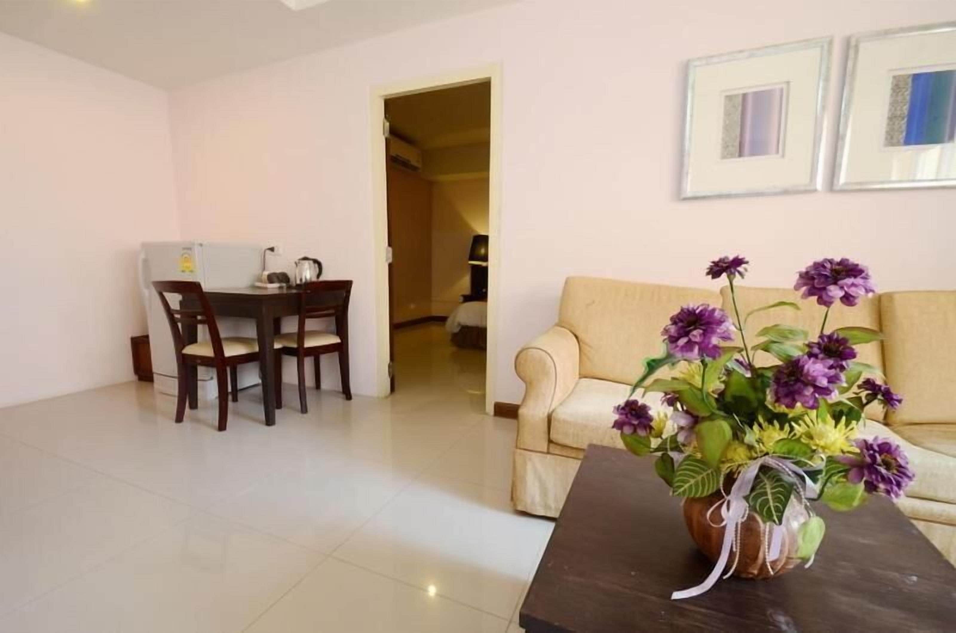 A living room with a dining area, a sofa, and a vase of flowers.