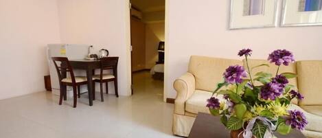 A living room with a dining area, a sofa, and a vase of flowers.