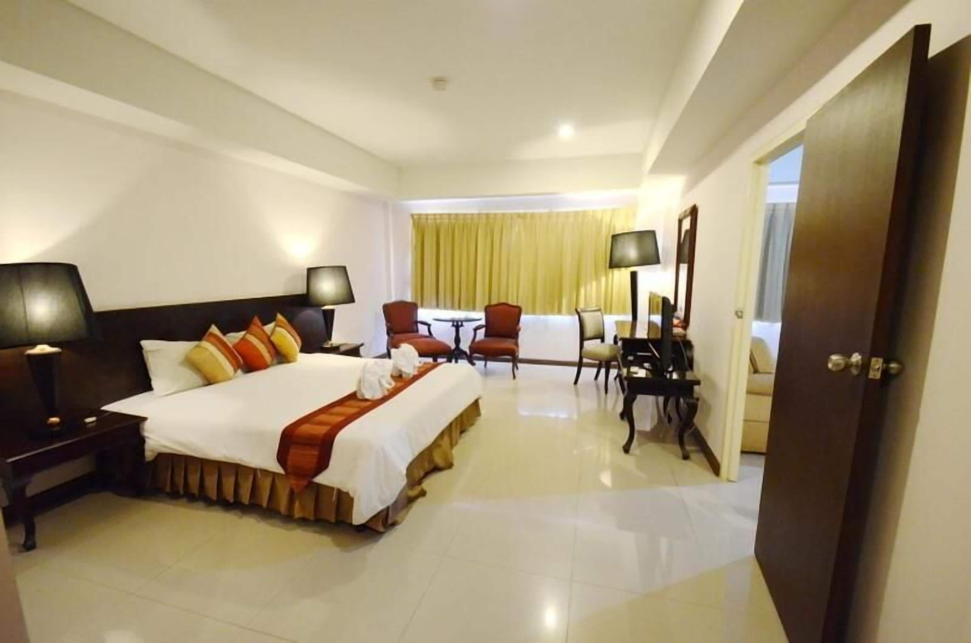 A hotel room with a large bed, bedside tables, a desk with a chair, and a view of the outside.