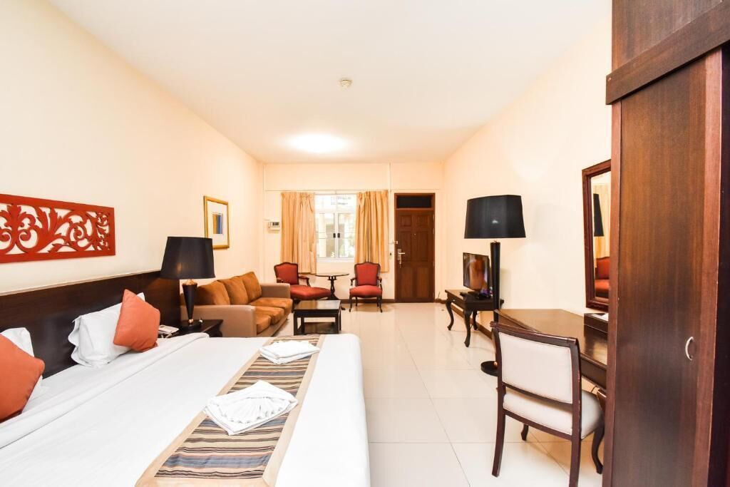 Une chambre d’hôtel avec un lit, un canapé, un bureau et une télévision.