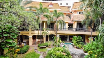 A multi-story building with a courtyard, balconies, and lush greenery.