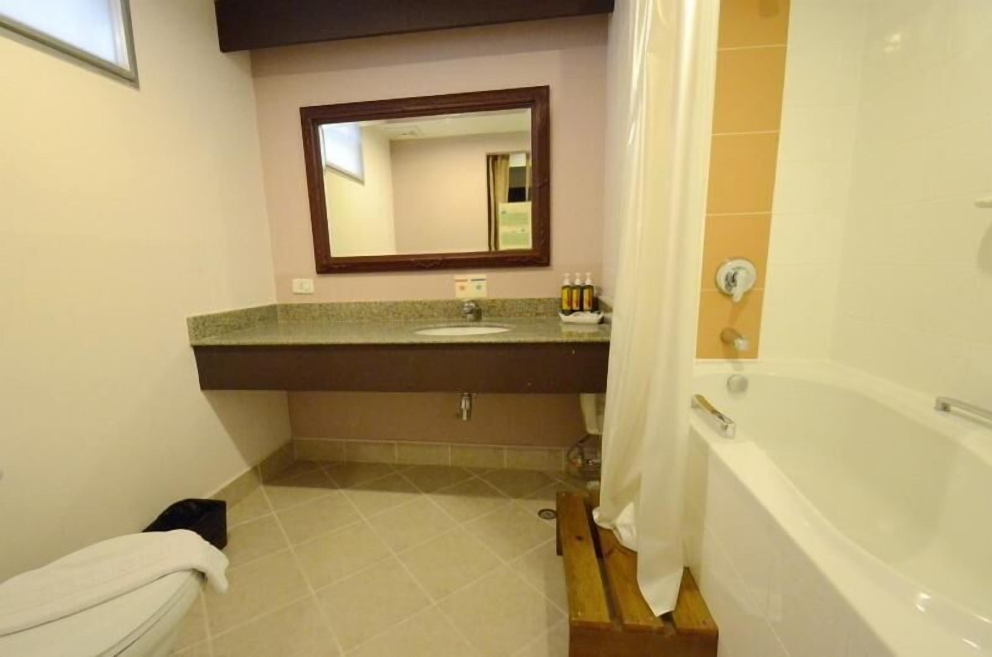 A bathroom with a bathtub, a sink, and a mirror.