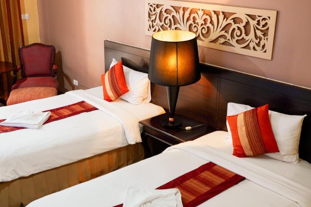 A hotel room with two beds, a nightstand, a lamp, and a decorative wall piece.
