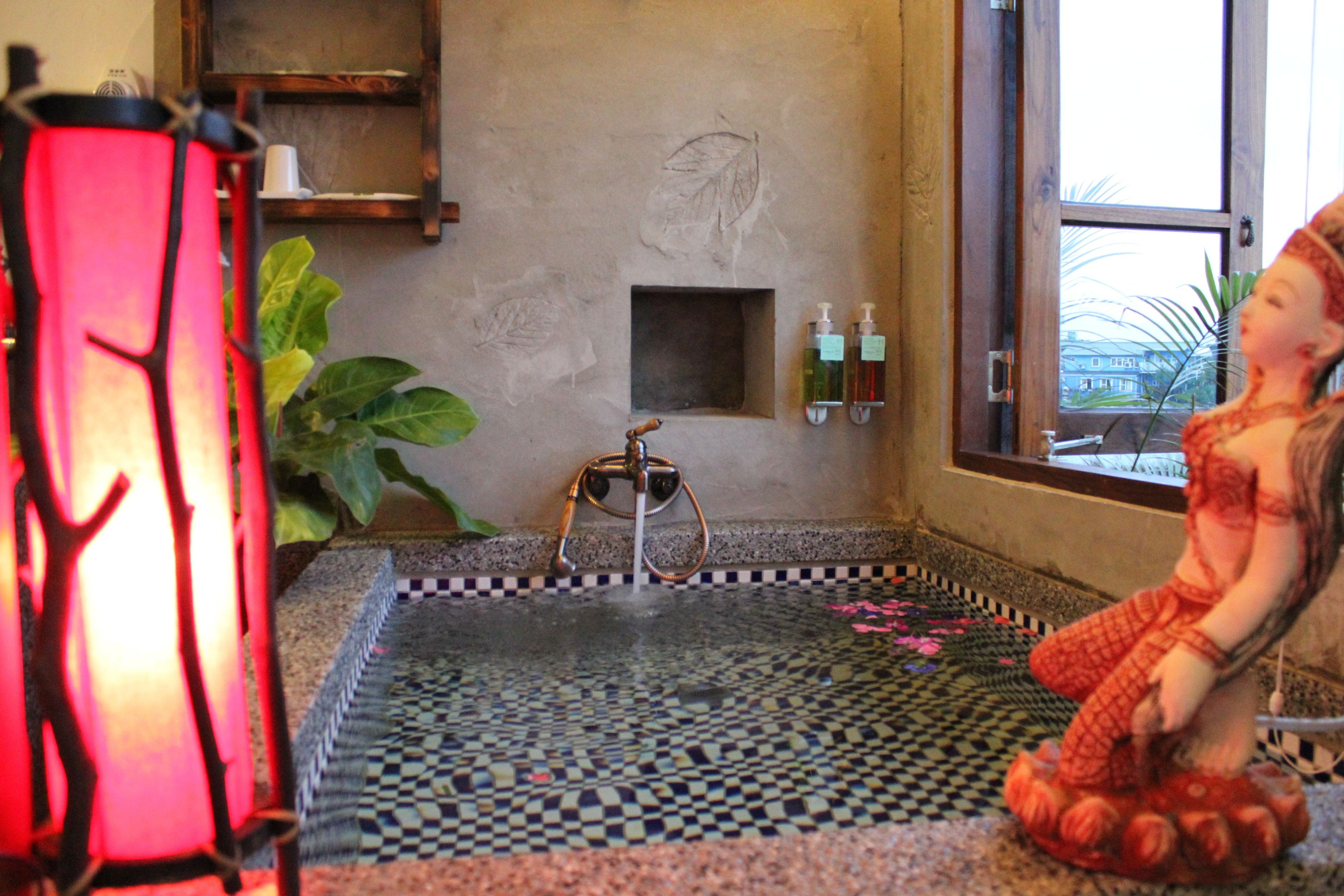 A room with a tiled floor, a small water feature, a statue, and a window with a view.