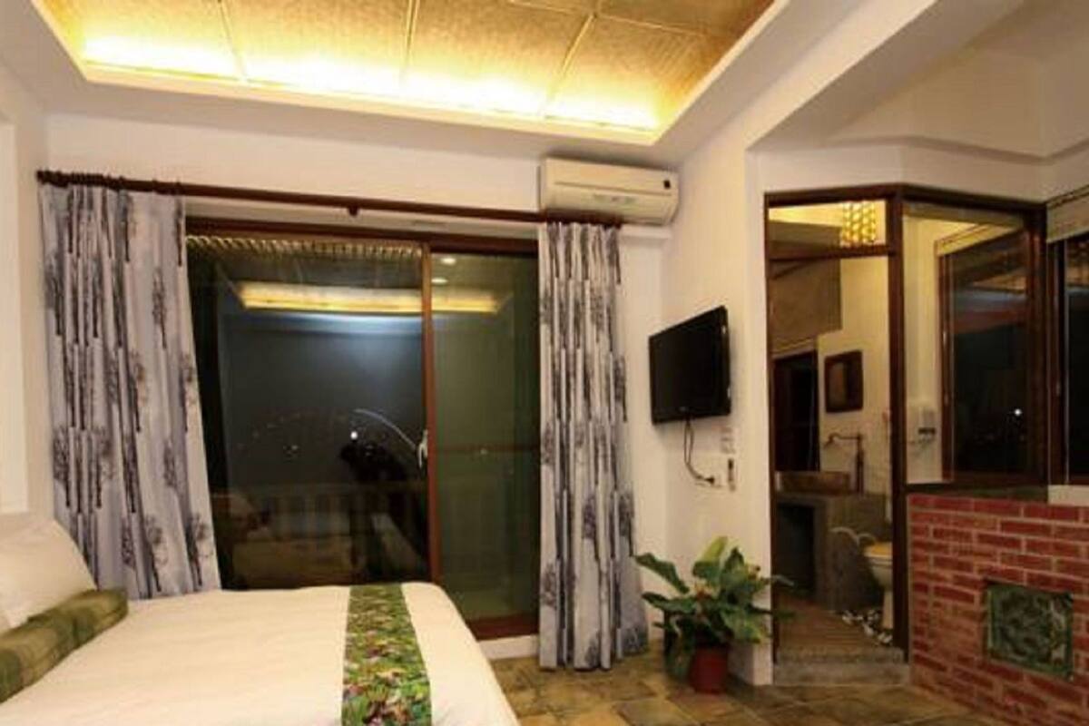 A hotel room with a bed, a TV, a sliding glass door, and a brick fireplace.