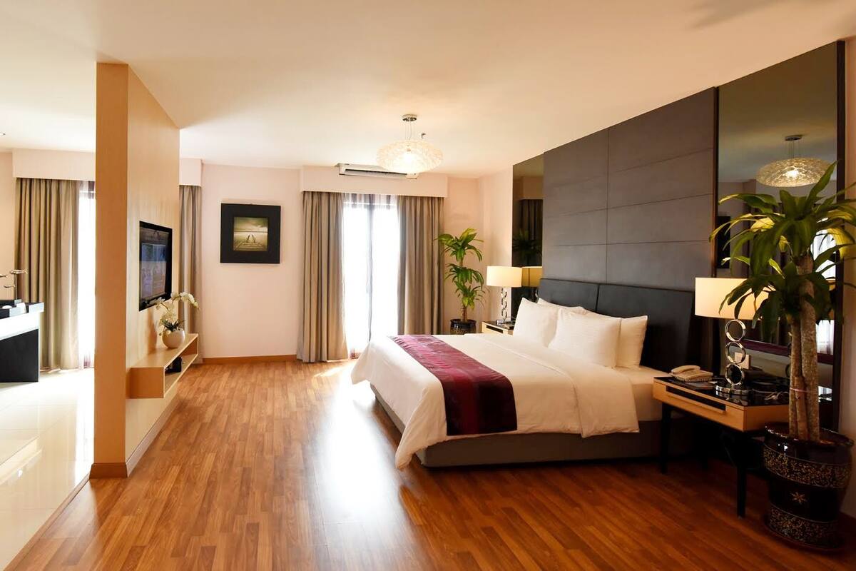 A modern hotel room with a large bed, a desk with a computer, a TV, and a large mirror.