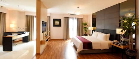 A modern hotel room with a large bed, a desk with a computer, a TV, and a large mirror.