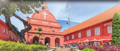 Christ Church Melaka, un sitio histórico con una fachada roja destacada, ventanas en arco y una gran cruz en la cúpula.