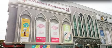 A building with the sign 'Dataran Pahlawan Mall' and multiple advertisements for shops and services.
