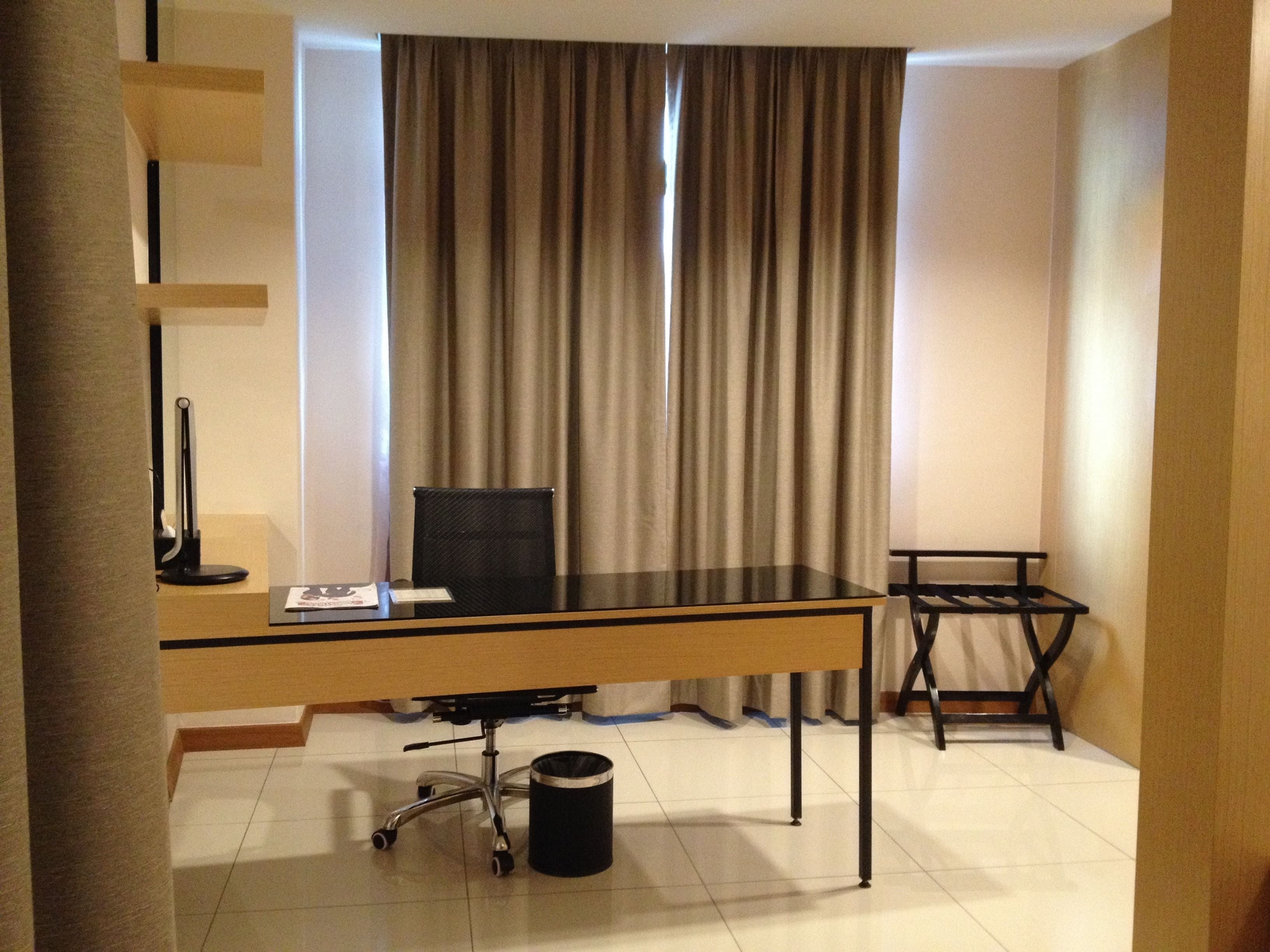 Ein Hotelzimmer mit Schreibtisch, Stuhl und Mülleimer.