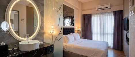 A modern hotel room with a round mirror, a marble sink, a bed with white bedding, a TV, and an air conditioning unit.