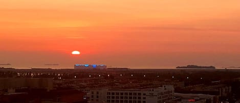 Un atardecer sobre una ciudad con edificios y un barco a lo lejos.