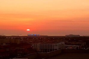 Un atardecer sobre una ciudad con edificios y un barco a lo lejos.