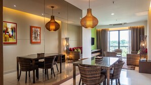 Un comedor moderno con una mesa de vidrio, sillas de mimbre e iluminación colgante.