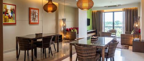 Un comedor moderno con una mesa de vidrio, sillas de mimbre e iluminación colgante.