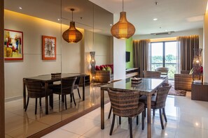 Un comedor moderno con una mesa de vidrio, sillas de mimbre e iluminación colgante.