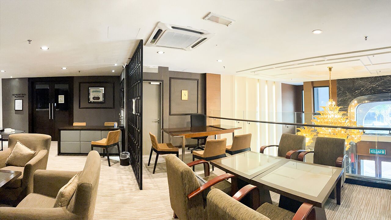 A modern hotel lobby with a dining area, a reception desk, and a view of the outside.