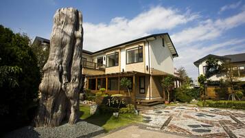 Stunning two-story home with a modern design, featuring a balcony and a beautifully maintained garden.