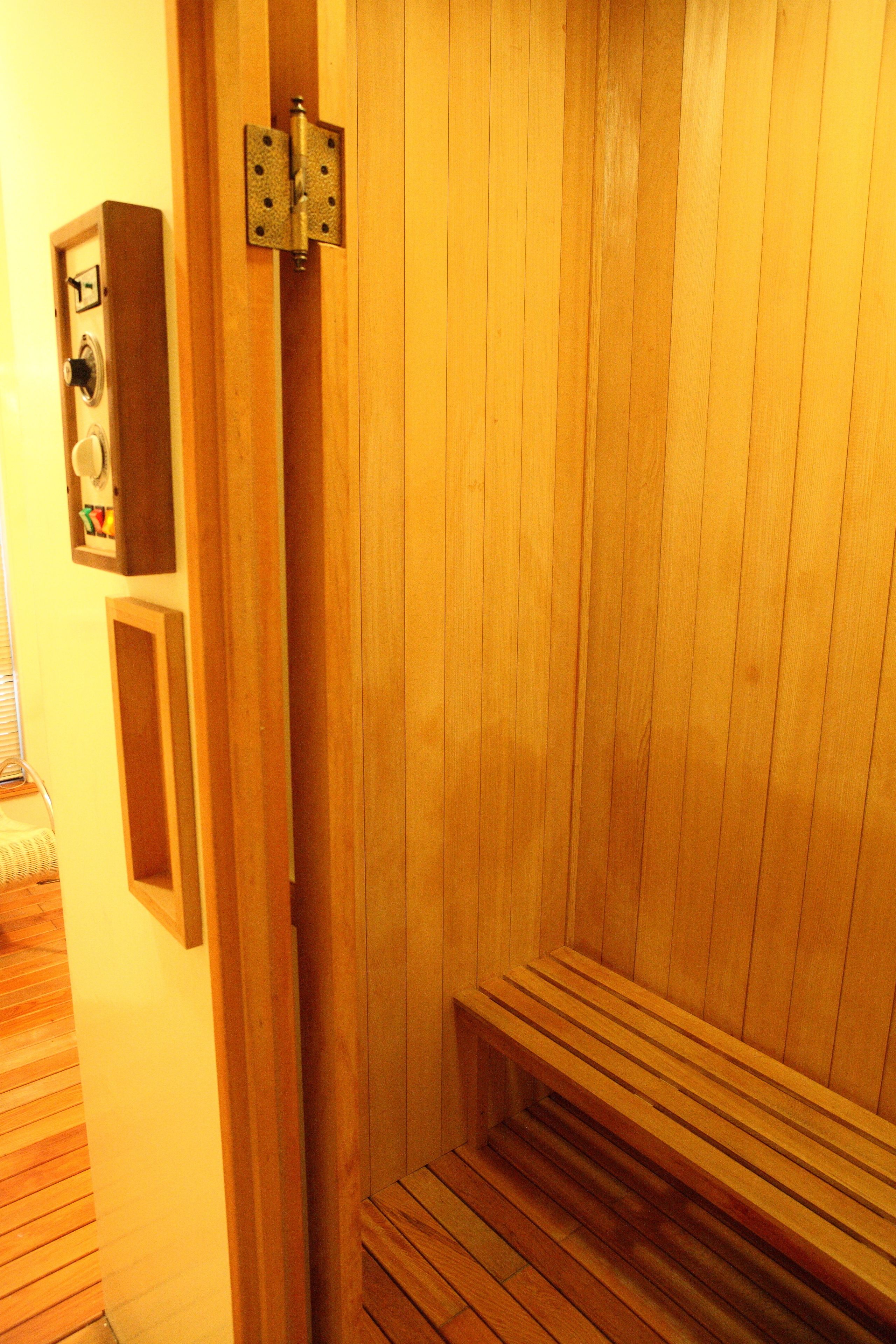 A wooden sauna with a bench and a control panel.