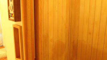 A wooden sauna with a bench and a control panel.