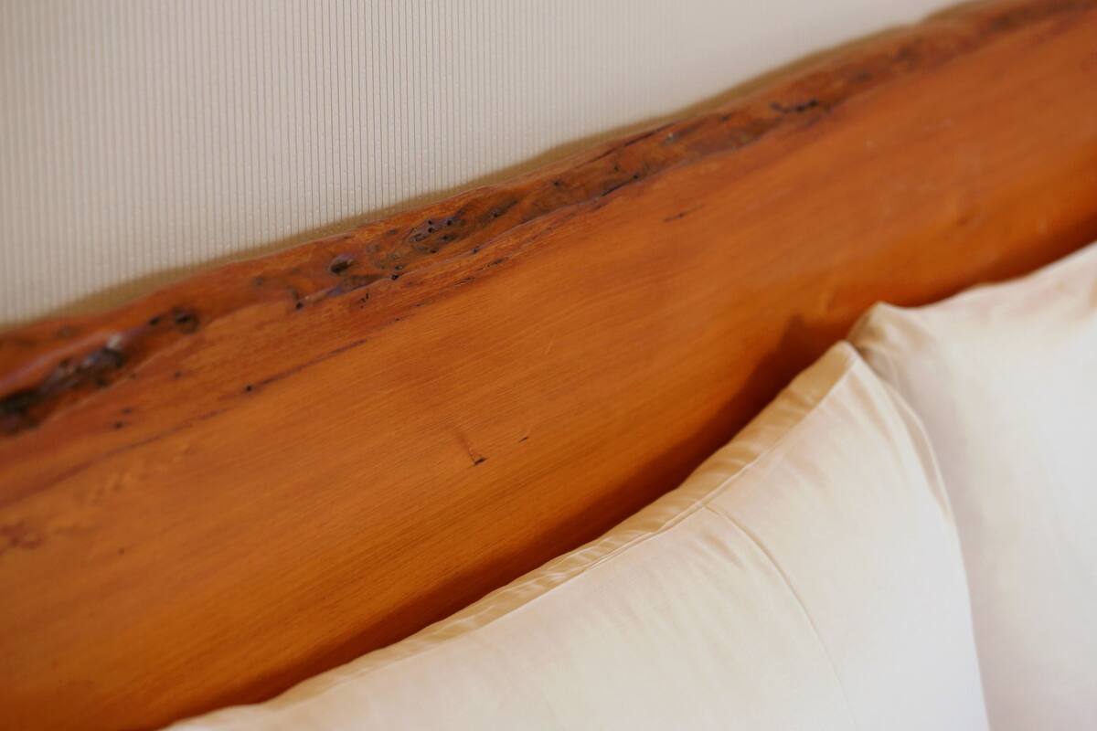 A wooden headboard with a textured finish and a white pillow.