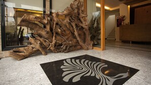 A reception area with a large wooden sculpture, a black and white patterned floor, and a glass door leading to a staircase. - Cypress House (Ji'an)