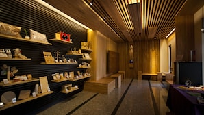 A modern interior with wooden shelves displaying various items, a bench, and a table with a television. - Cypress House (Ji'an)