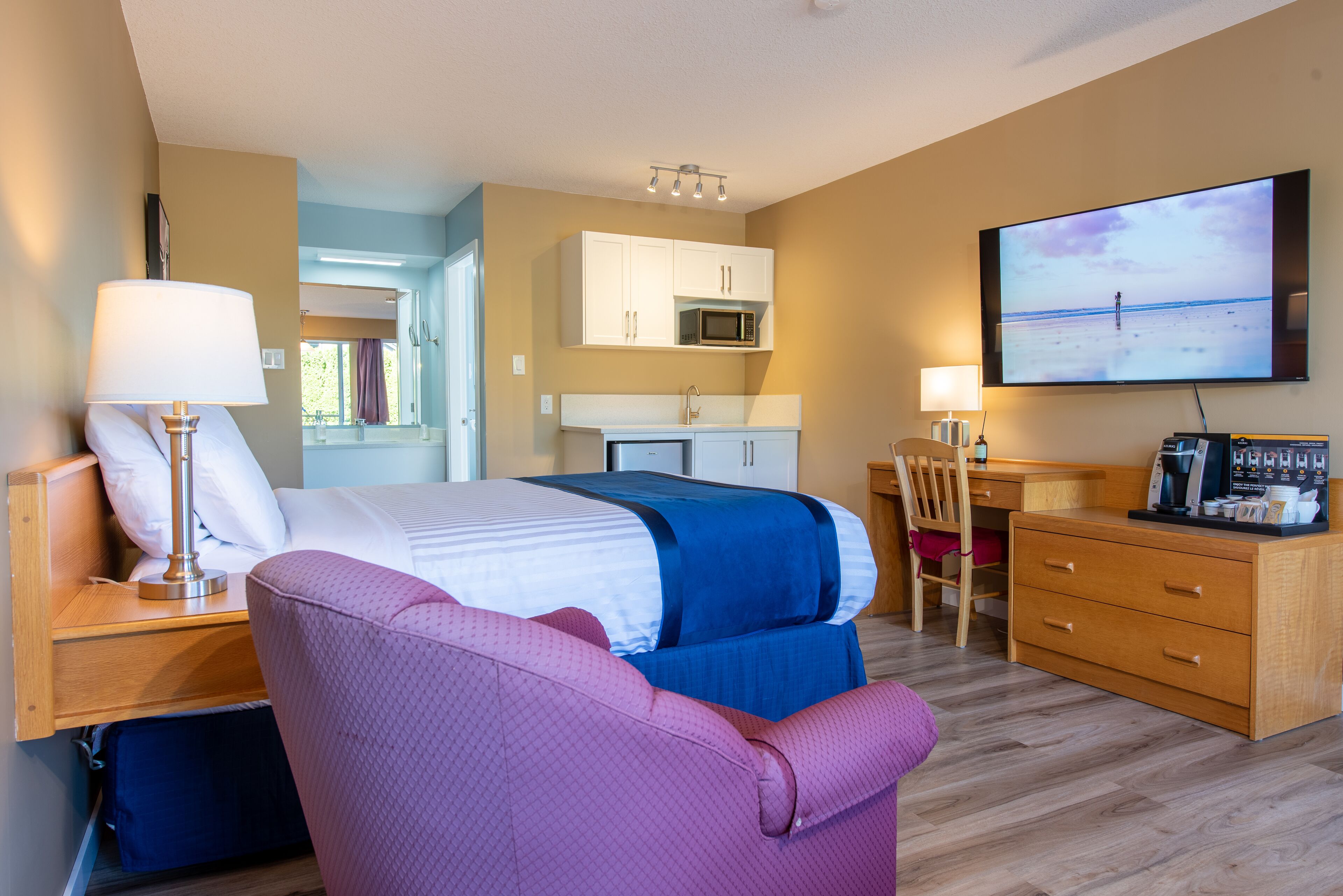 Una habitación de hotel con una cama, un escritorio, una silla, un televisor y un rincón americano.