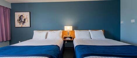 A hotel room with two beds, a nightstand with a lamp, a painting on the wall, and a window with curtains.
