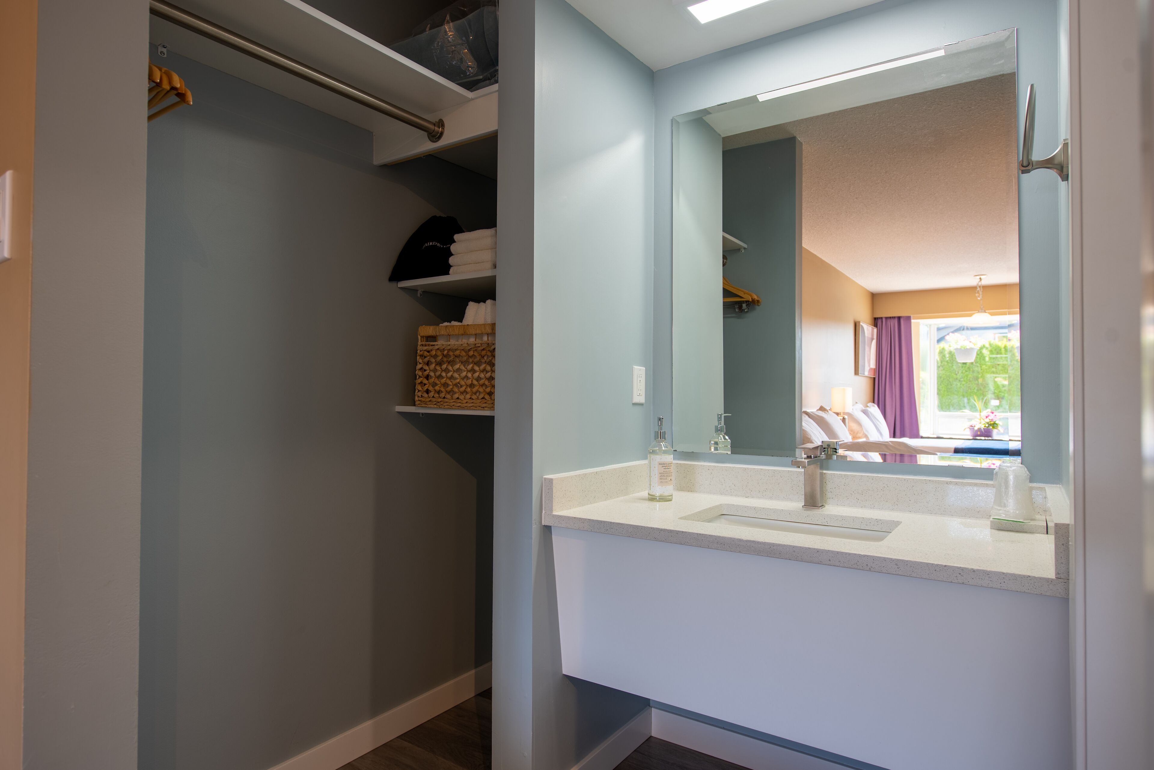 A bathroom with a white sink, a mirror, and a towel rack.