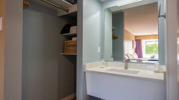 A bathroom with a white sink, a mirror, and a towel rack.