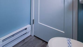 Un baño con una puerta blanca, toallero y retrete.