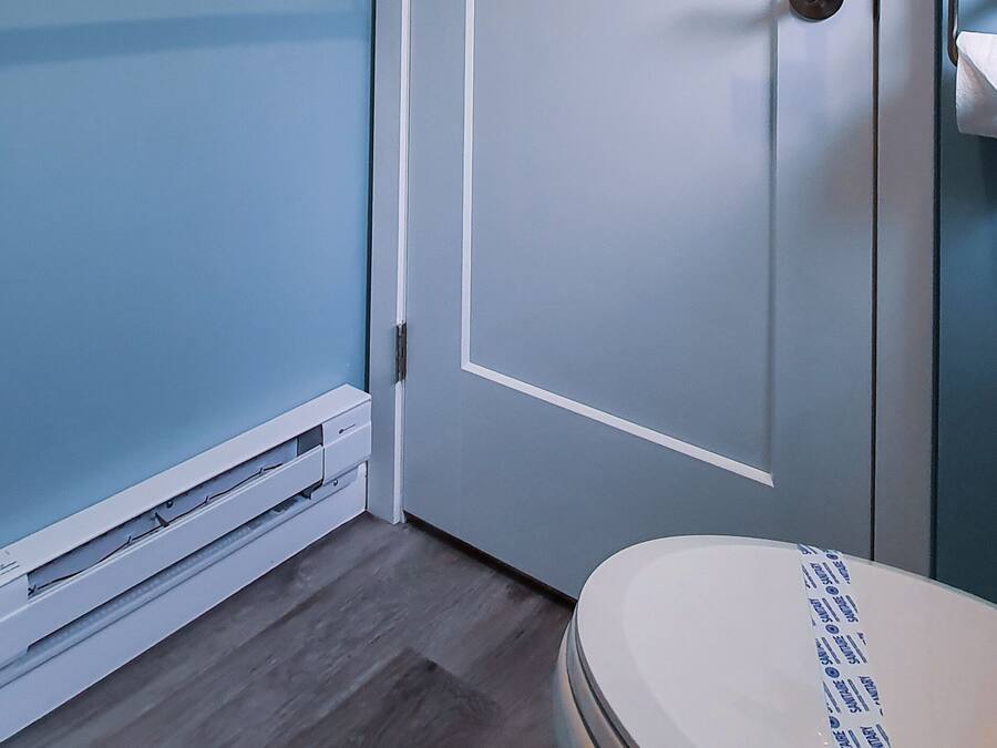 Un baño con una puerta blanca, toallero y retrete.