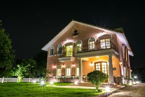 Una casa a due piani con un balcone, ampie finestre e un portico luminoso.