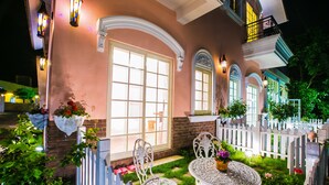 A well-lit garden with a white picket fence, a table with chairs, and a balcony with a railing. - Belle Garden Yillan Villa (Dongshan)